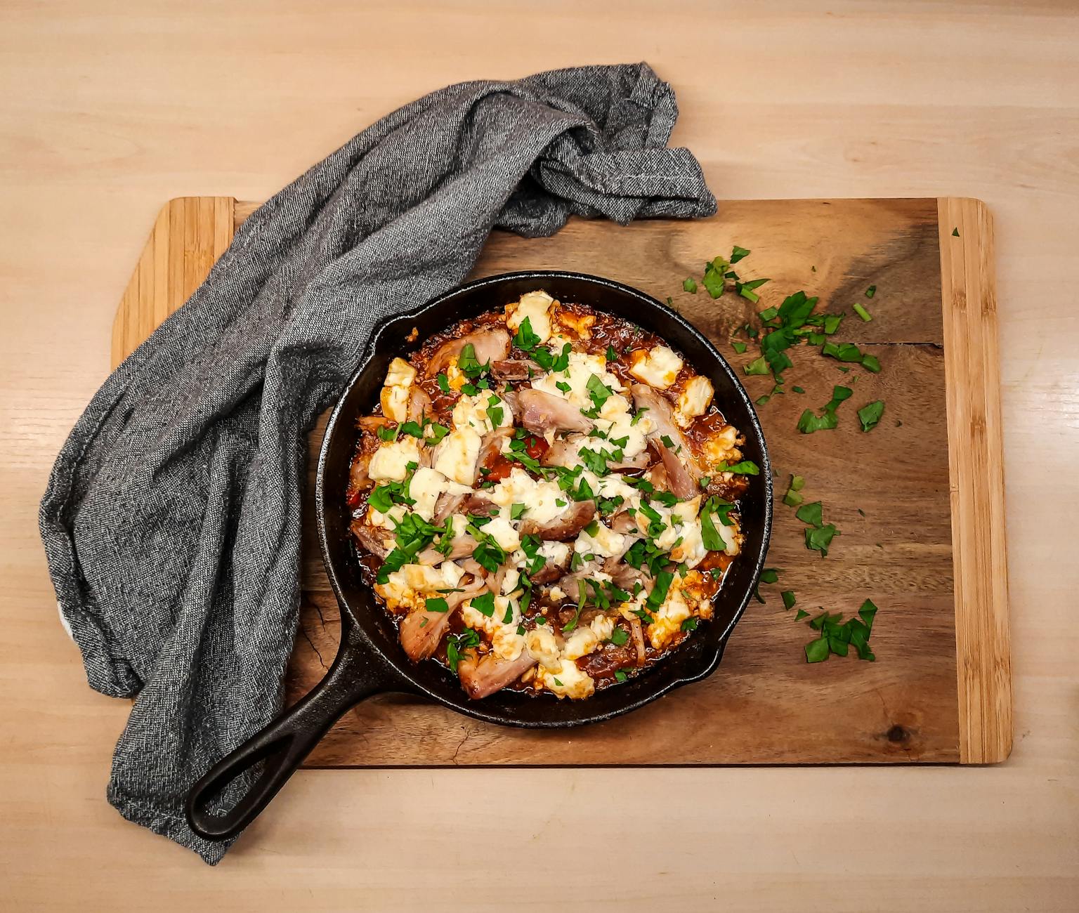 Skillet of hot honey feta chicken thighs topped with crumbled feta and herbs