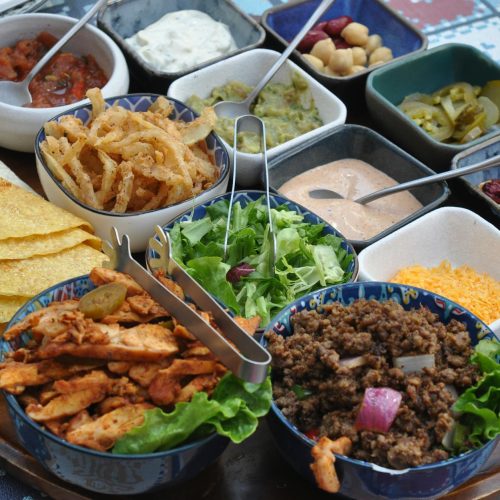 Mexican tacos with seasoned beef, warm tortillas, cilantro, lime wedges, and fresh toppings on a serving platter