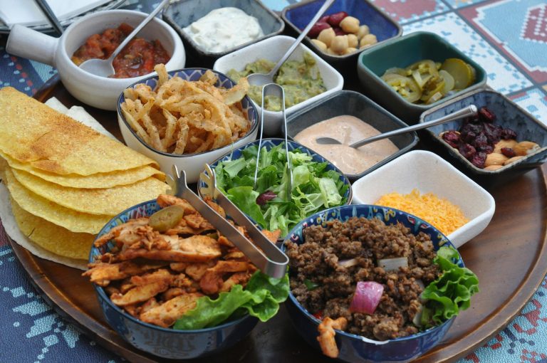 Mexican tacos with seasoned beef, warm tortillas, cilantro, lime wedges, and fresh toppings on a serving platter