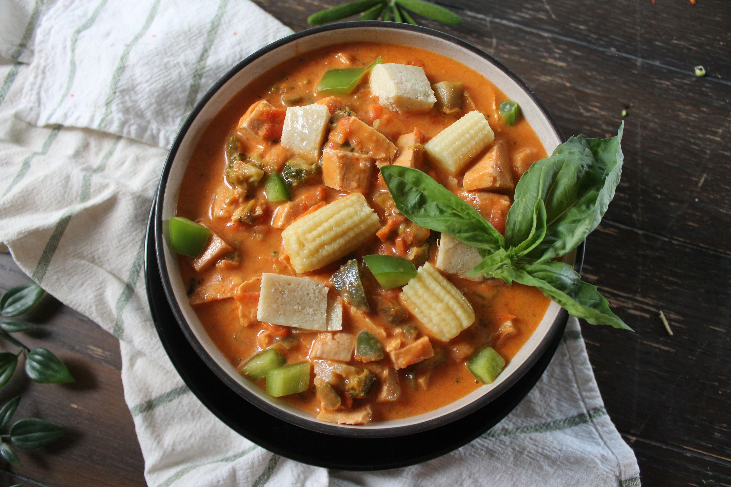Appetizing Thai red curry dish with tofu and fresh vegetables in a bowl.