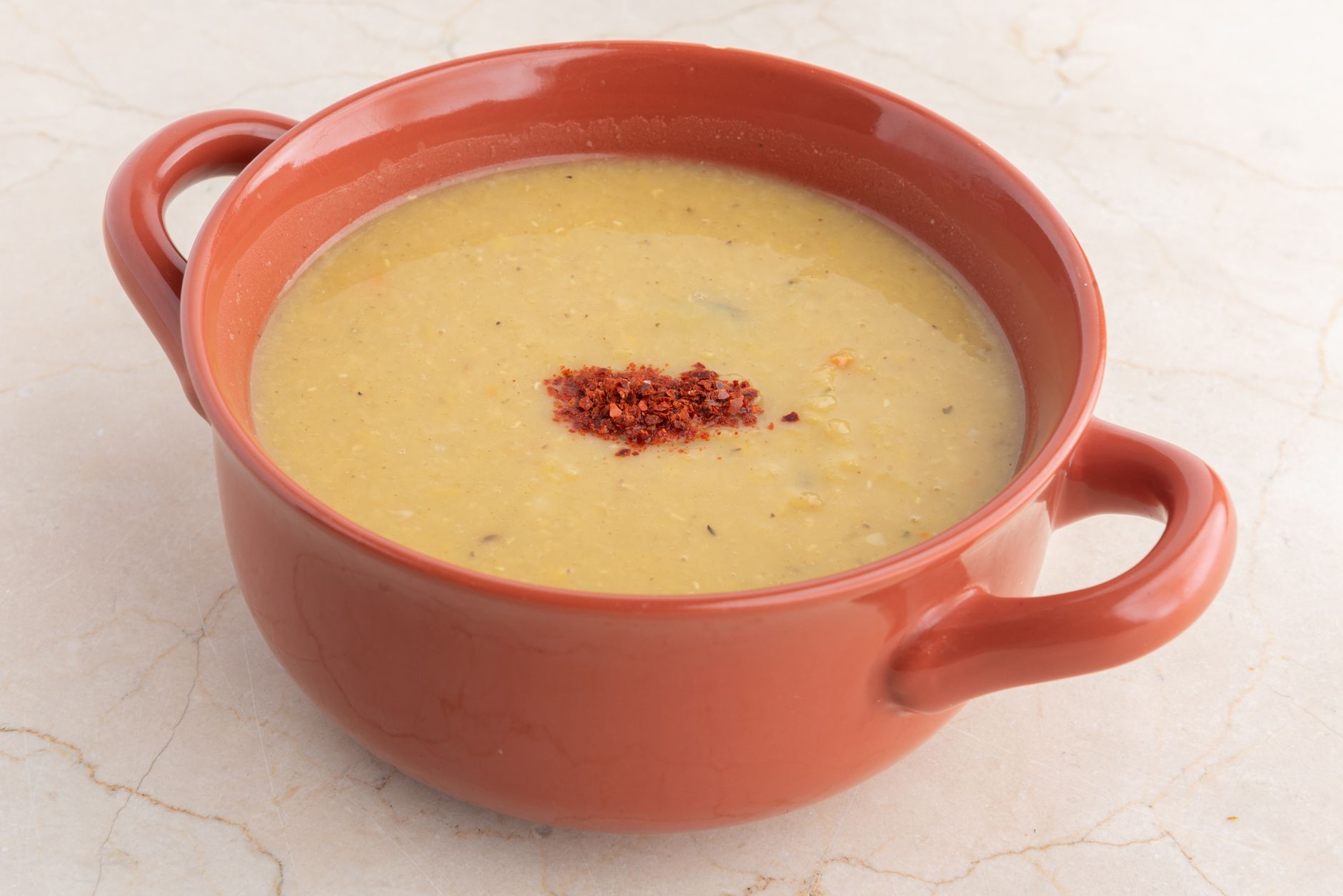 Creamy Turkish red lentil soup mercimek in a bowl with lemon and chili oil drizzle