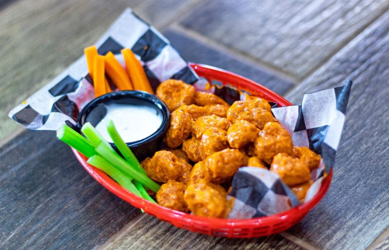 baked crispy cauliflower buffalo wings on tray with ranch and celery