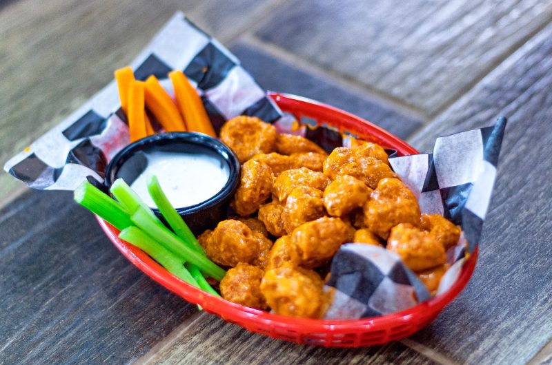 baked crispy cauliflower buffalo wings on tray with ranch and celery