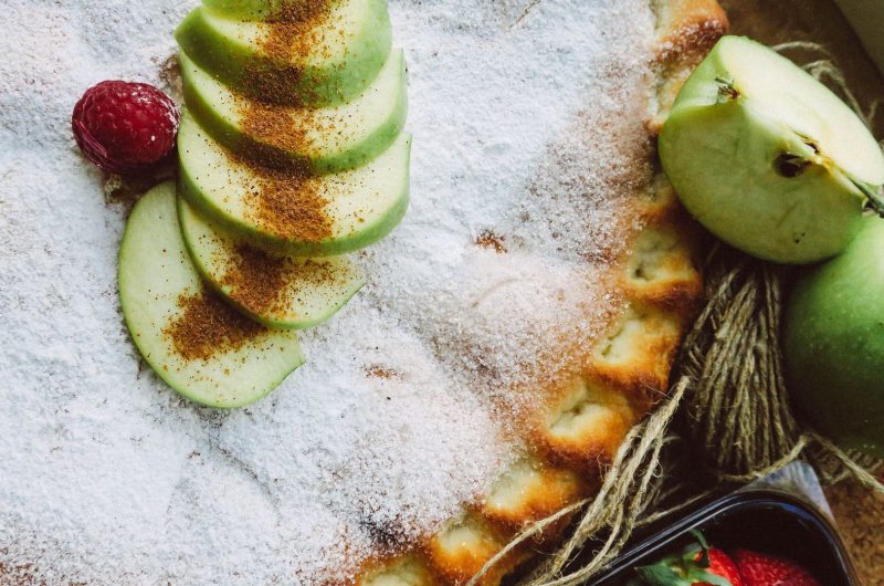 slice of classic apple pie with flaky lattice crust on a plate with vanilla ice cream