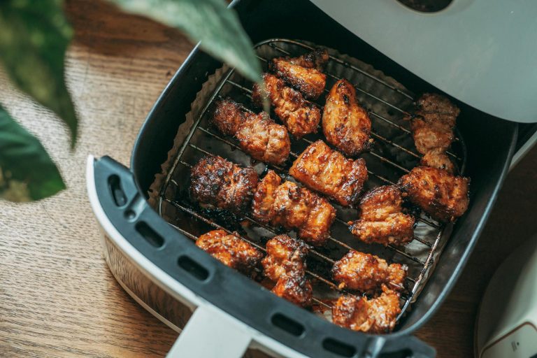 Pile of crispy golden air fryer chicken wings on a platter with dipping sauce and celery sticks