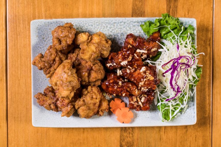 crispy Korean fried chicken glazed with sweet spicy sauce, garnished with sesame seeds and scallions