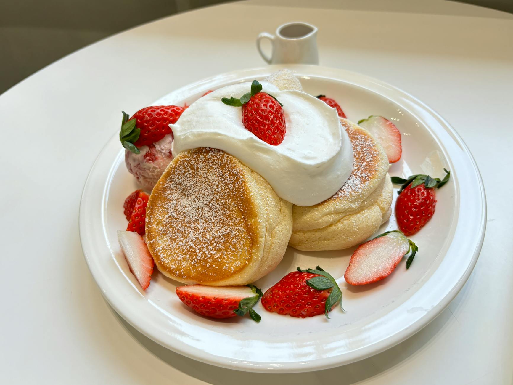 Stack of fluffy Japanese souffle pancakes topped with berries and whipped cream