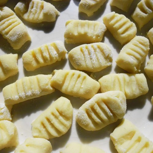 Uncooked homemade potato gnocchi with ridges on a white surface