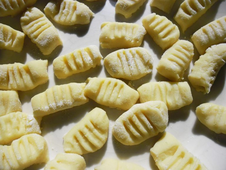 Soft homemade potato gnocchi on a floured board with sage butter sauce