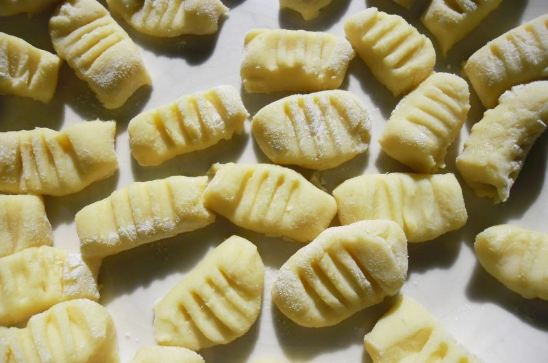 Soft homemade potato gnocchi on a floured board with sage butter sauce