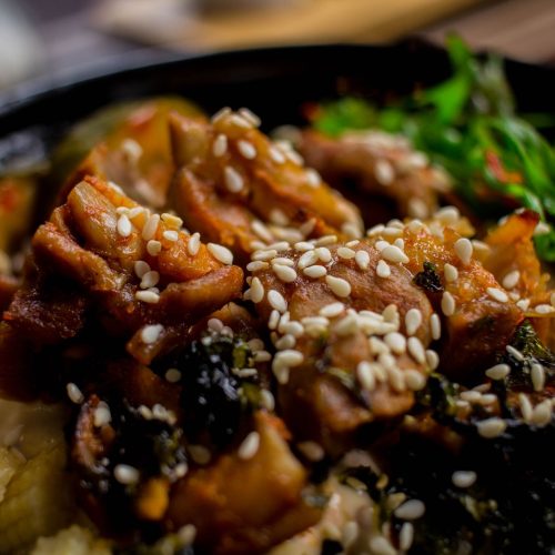 Chinese honey sesame chicken served over rice with sesame seeds and green onions