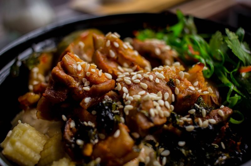 Chinese honey sesame chicken served over rice with sesame seeds and green onions