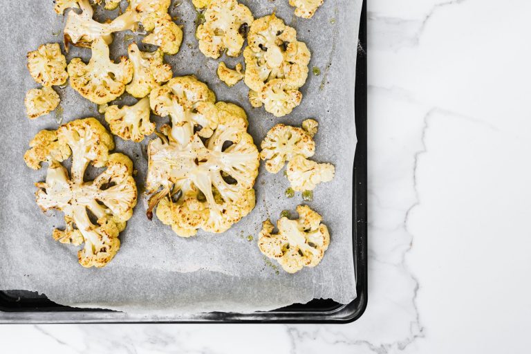 baked keto cauliflower mac and cheese in a casserole dish with golden bubbly cheese topping