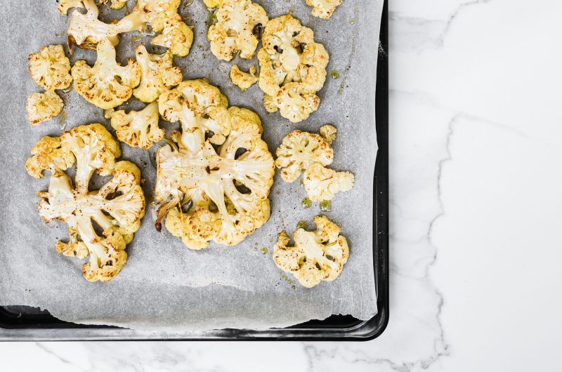 baked keto cauliflower mac and cheese in a casserole dish with golden bubbly cheese topping
