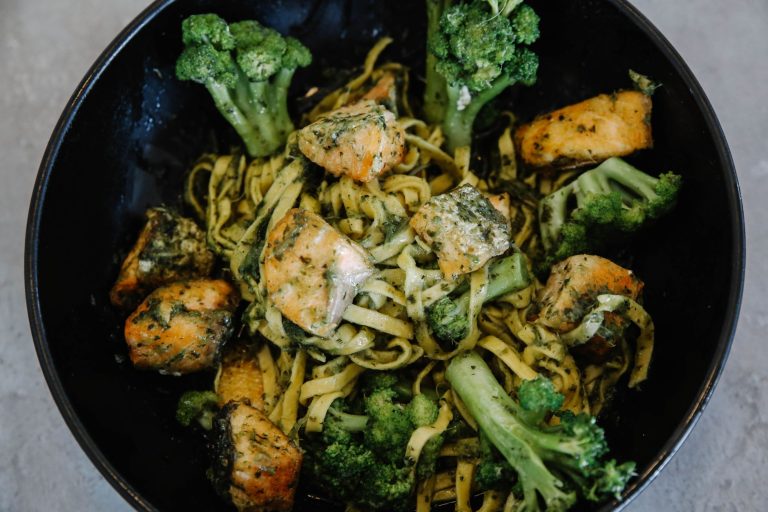 colorful healthy Mediterranean salmon bowl with quinoa, vegetables, and yogurt sauce in a white dish