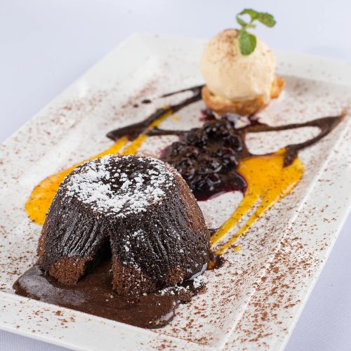 Warm chocolate lava cake on a white plate with ice cream and oozing molten center