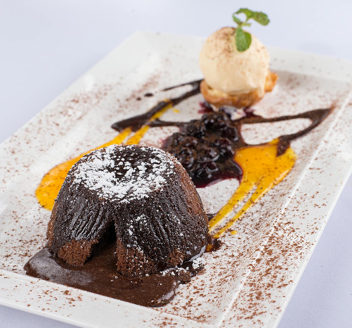 Warm chocolate lava cake on a white plate with ice cream and oozing molten center