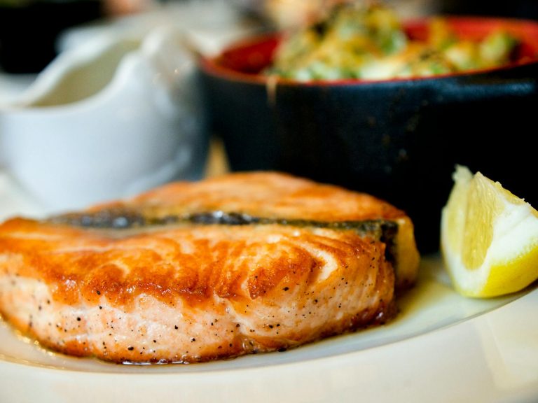 One pot lemon garlic salmon with potatoes, broccolini, and lemon in a skillet