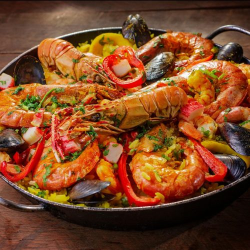 overhead view of Spanish seafood paella with shrimp mussels and lemon in a wide pan