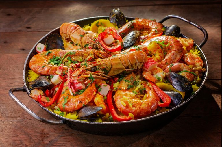 overhead view of Spanish seafood paella with shrimp mussels and lemon in a wide pan