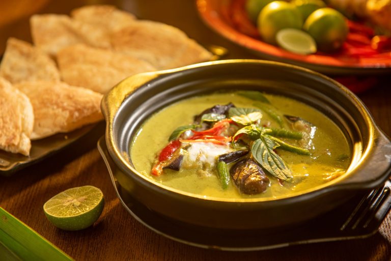 bowl of authentic Thai green curry with chicken and vegetables over jasmine rice