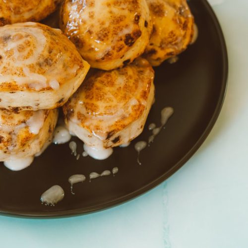 Cinnamon rolls with visible swirls and drizzled icing on a dark plate
