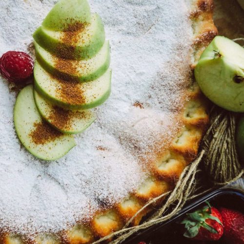 Sugar-dusted apple tart topped with thin fanned green apple slices