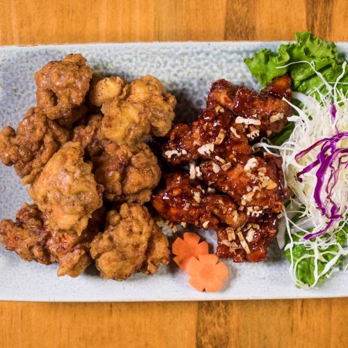 crispy Korean fried chicken glazed with sweet spicy sauce, garnished with sesame seeds and scallions