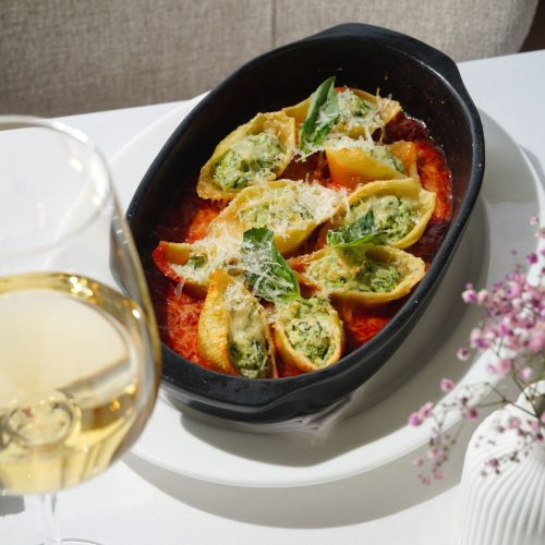 Jumbo pasta shells stuffed with spinach and ricotta, baked in tomato sauce in a black dish