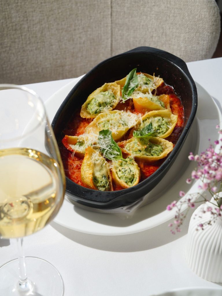 Jumbo pasta shells stuffed with spinach and ricotta, baked in tomato sauce in a black dish