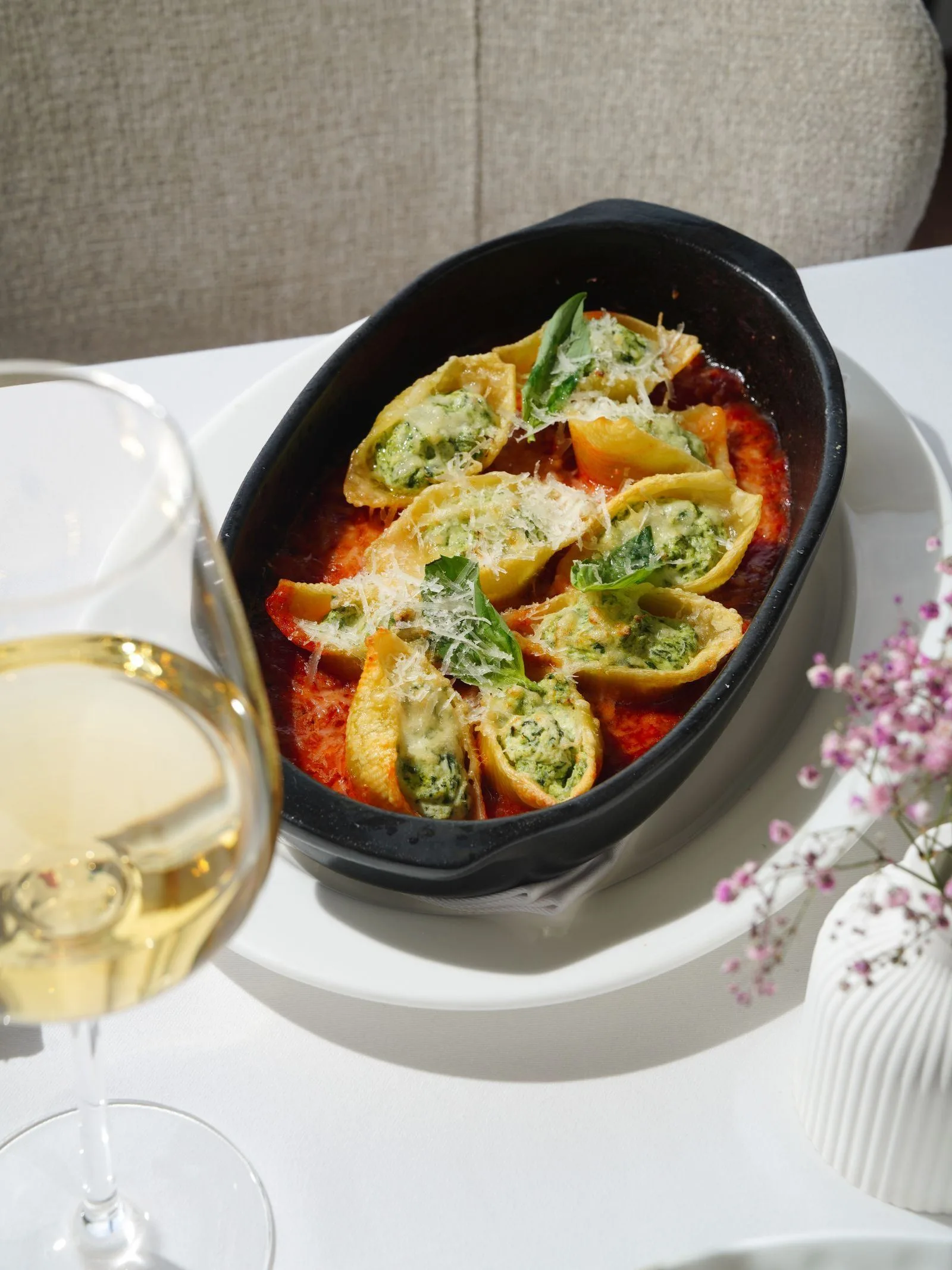 Jumbo pasta shells stuffed with spinach and ricotta, baked in tomato sauce in a black dish